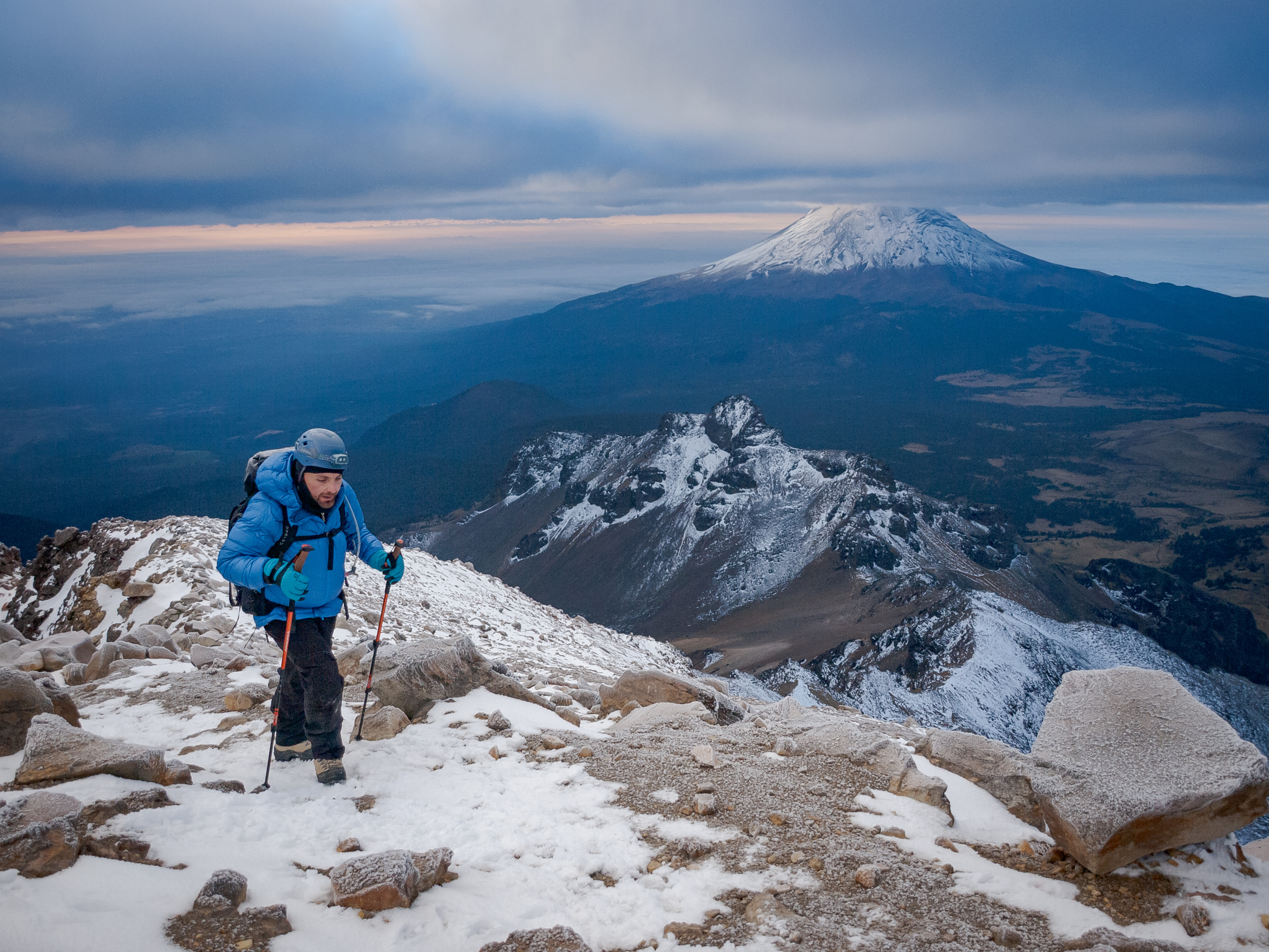 Climber on the rocky summit ridge with Popocatépetl and the valley 4,000m below