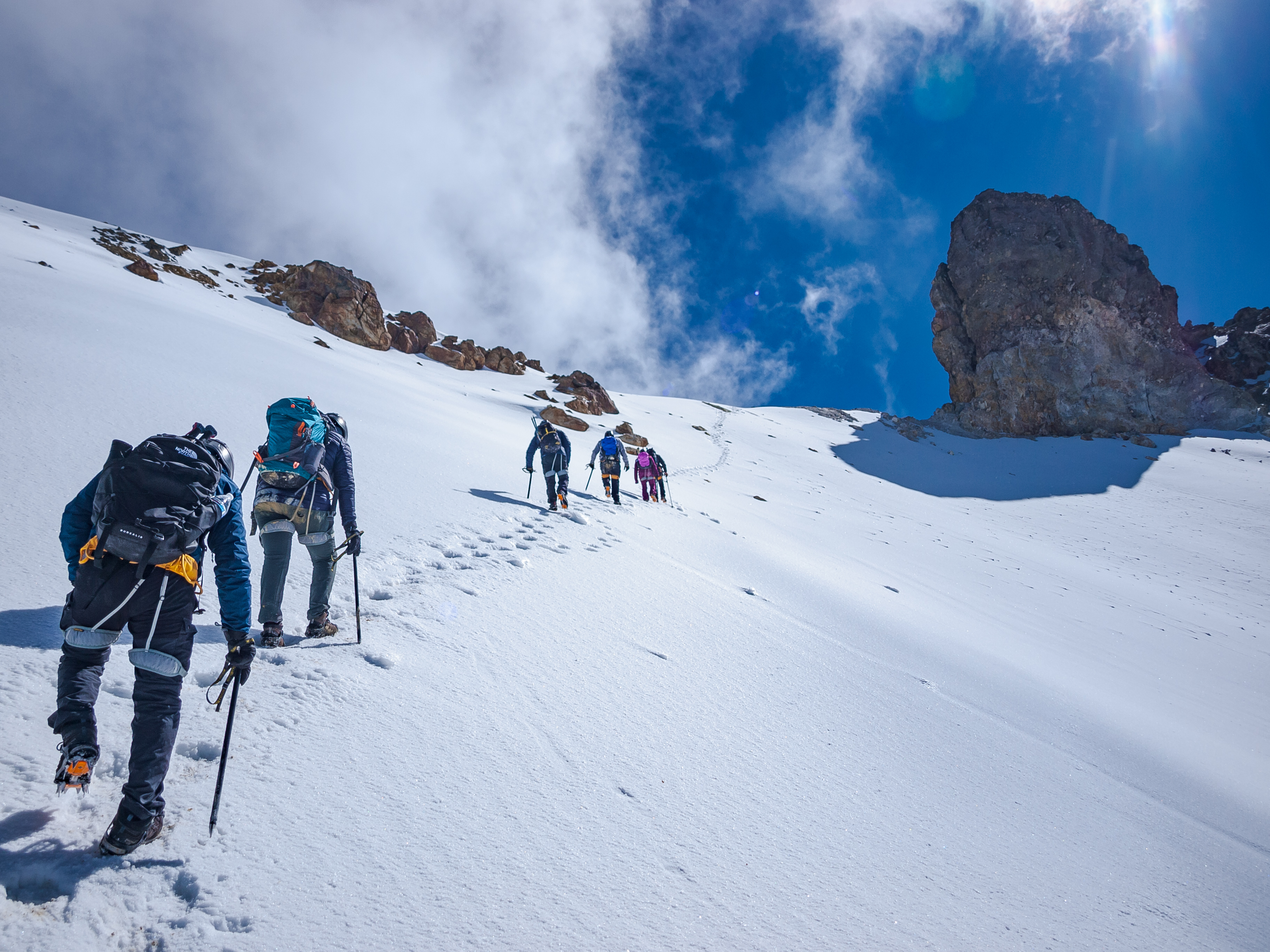 Group roped up and ascending Pico de Orizaba glacier under a brilliant blue sky